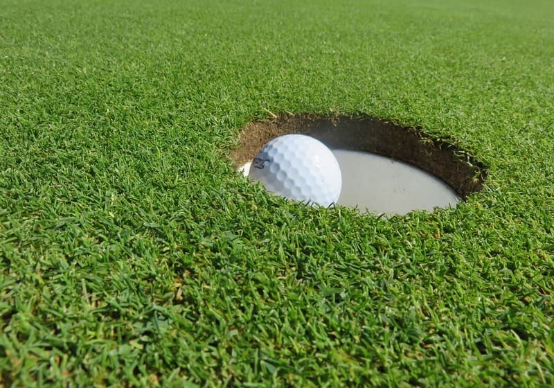 Golf ball going into golf hole